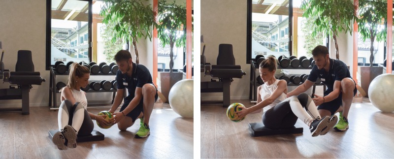 personal trainer insegna alla ragazza come eseguire l'esercizio Russian Twist per avere un addome forte