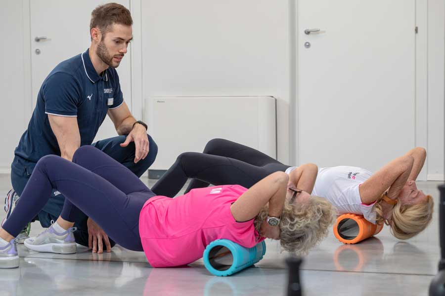 due donne si allenano insieme e fanno il foam roller per non avere mal di schiena 