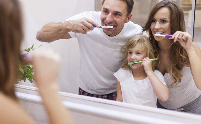 famiglia composta da mamma, papà e figlia si lavano i denti insieme 