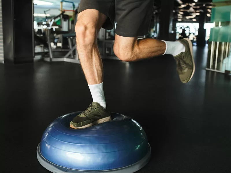 uomo che fa esercizi di Isometria e Propriocezione per presciistica con  bosu ball