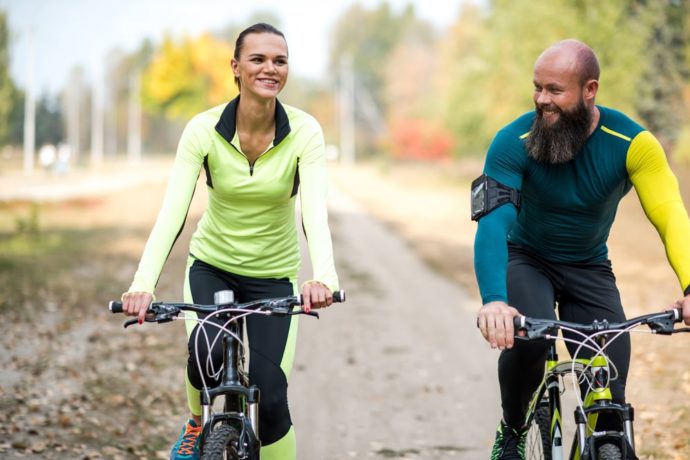 coppia uomo e donna felici vanno in bici perché vogliono dimagrire. 