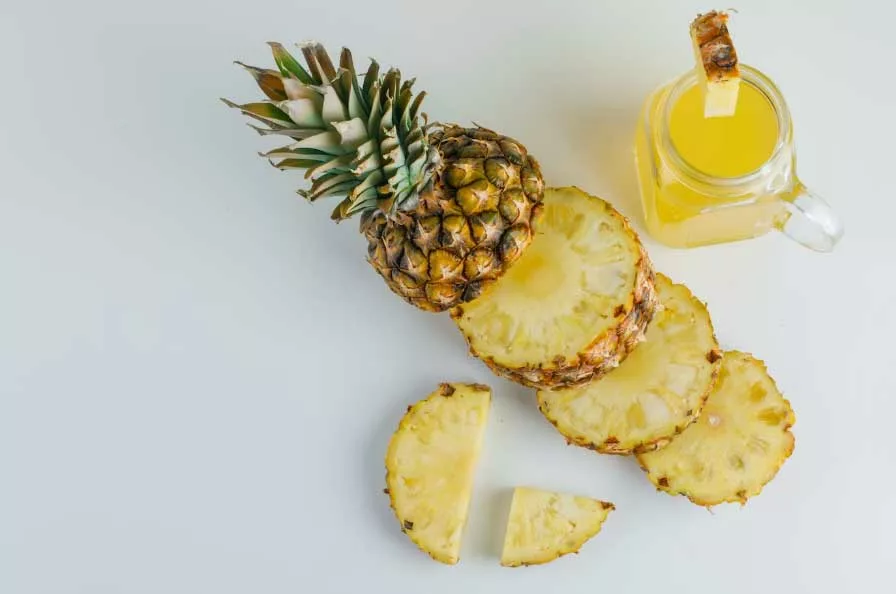 ananas tagliato a fette e bicchiere di succo d'ananas