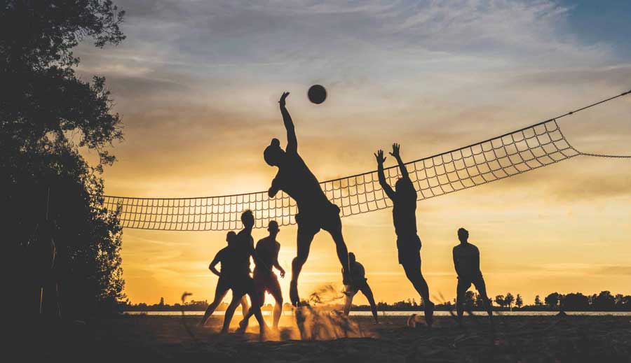 gruppo di amici in spiaggia giocano al tramondto a beach volley