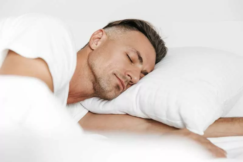 uomo che dorme bene a letto con la testa sul cuscino