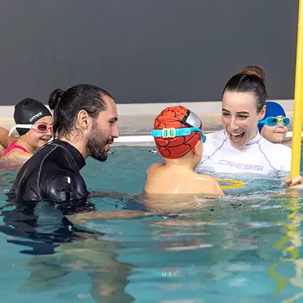 Corso di Acquaticità - istruttori seguono bambino e gli insegnano a nuotare