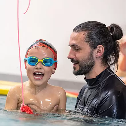 Corso di Acquaticità - bambino sorridente impara a nuotare con istruttore a Padova