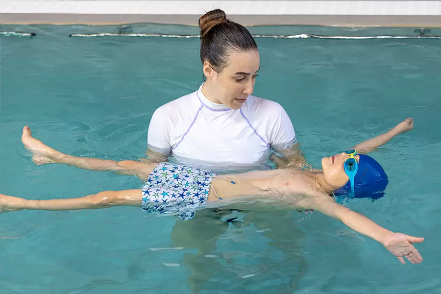 Istruttrice insegna a galleggiare a un bambini in piscina a Padova 