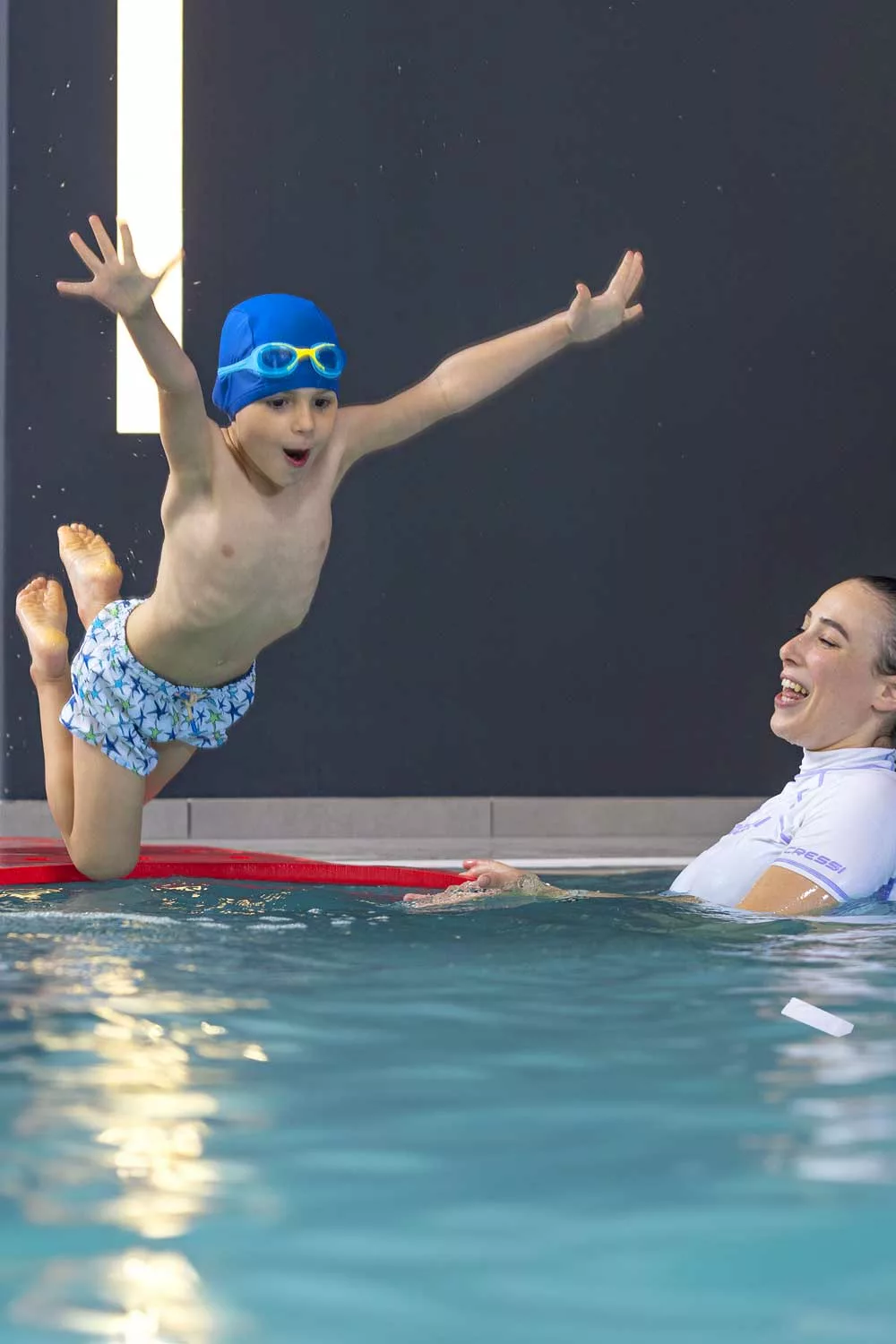 bambini si tuffa e impara a nuotare in piscina con la supervisione di un personal trainer