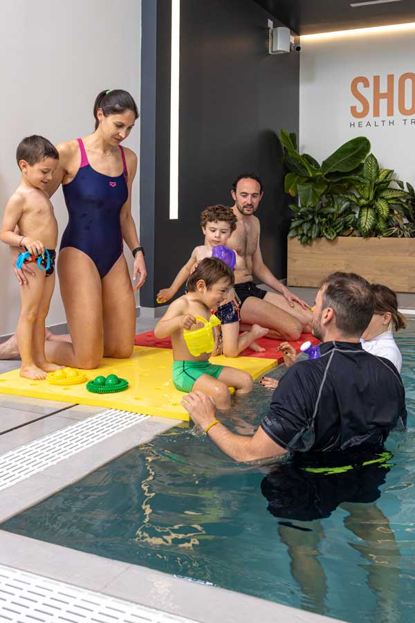 bambini a bordo piscina con i genitori pronti per il corso di nuoto