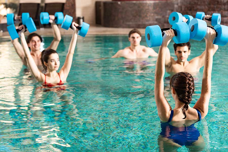 gruppo di donne con le braccia alzate in piscina si allenano facendo acquafitness