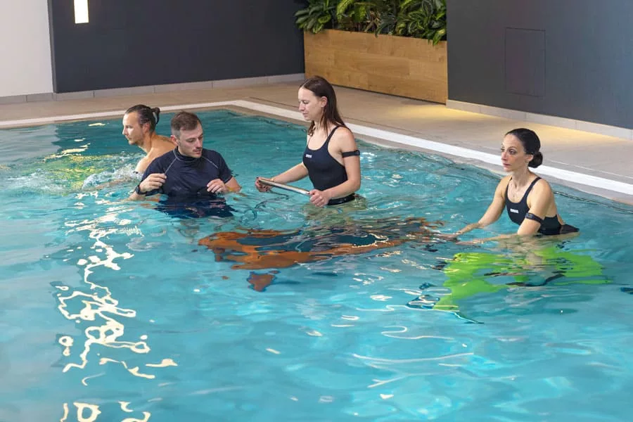 gruppo di persone di allenano in piscina con personal trainer