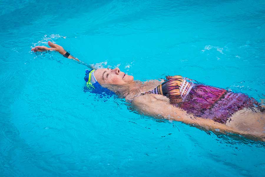 donna nuota in piscina a dorso