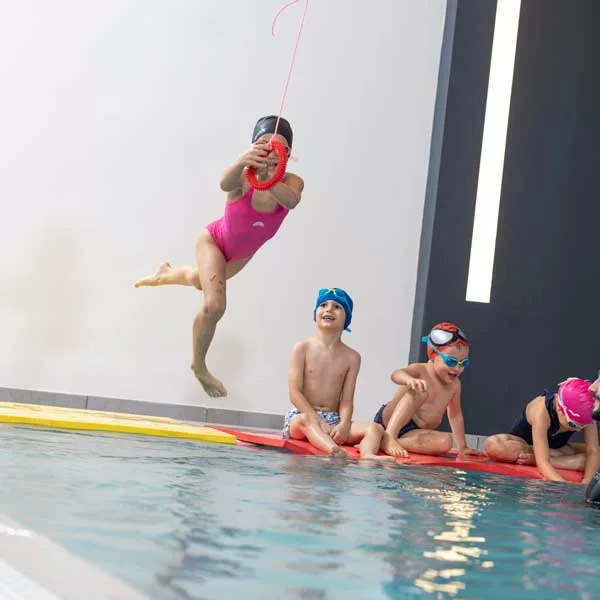 bambina si tuffa in piscina prendendo il cerchio