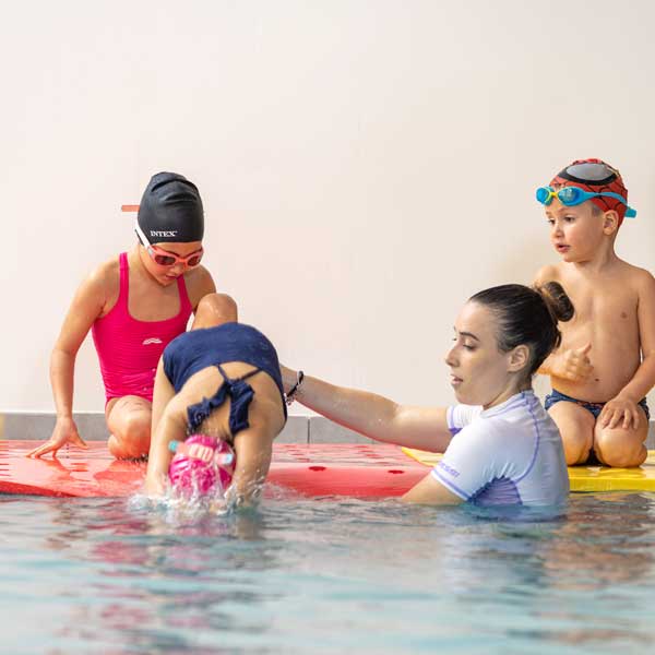 personal trainer insegna alla bambina come tuffarsi in piscina