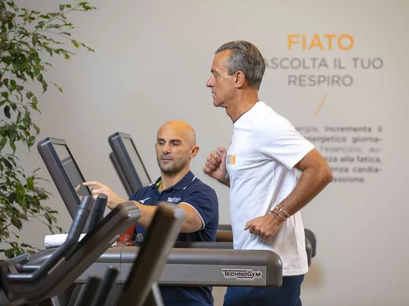 uomo si allena con personal trainer e fa cardio in palestra 