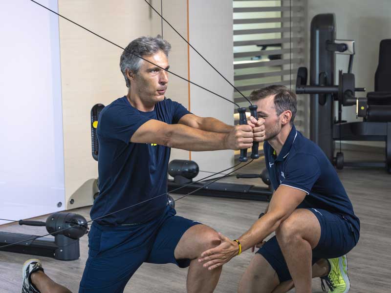 uomo si allena con personal trainer in palestra 