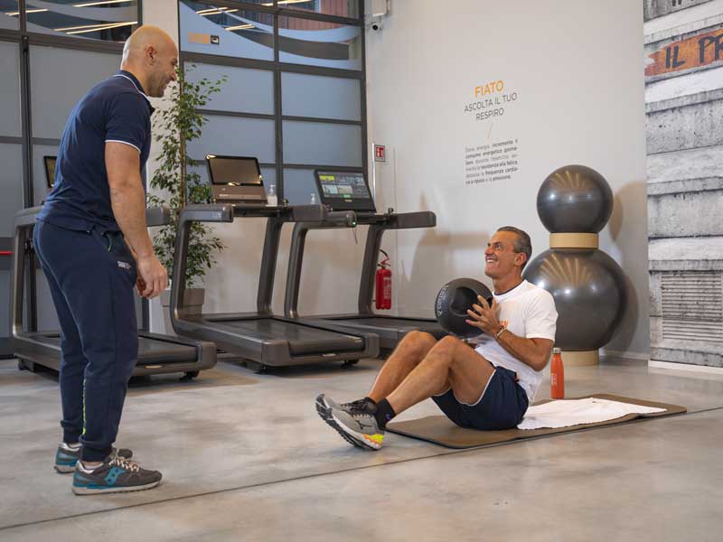 uomo si allena in palestra in estate con il personal trainer