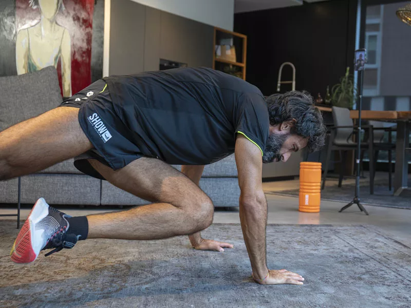 uomo fa allenamento di fiato nel salotto di casa seguito da un personal trainer online 