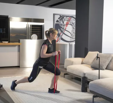 donna a casa con gli elastici si allena seguita dal suo personal trainer online