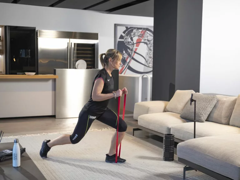 donna a casa con gli elastici si allena seguita dal suo personal trainer online