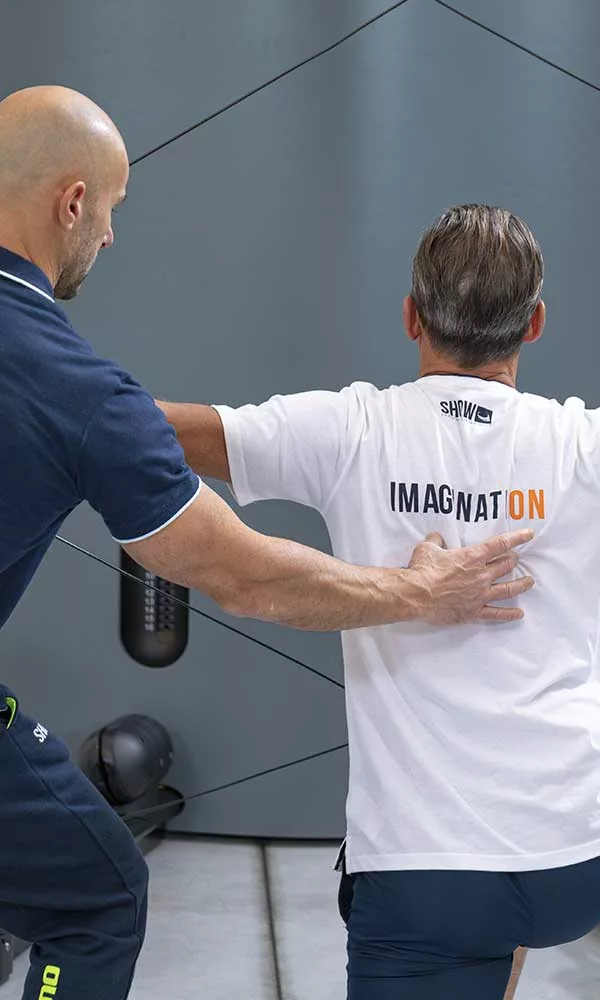 uomo fa esercizi di ginnastica posturale in palestra seguito da personal trainer