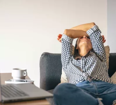 donna sedentaria sta distesa sul divano con le braccia sopra il viso