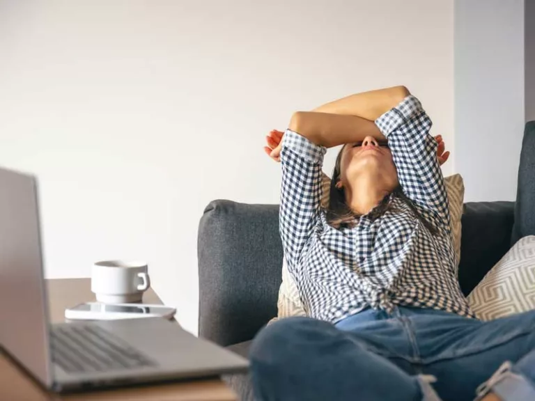 donna sedentaria sta distesa sul divano con le braccia sopra il viso