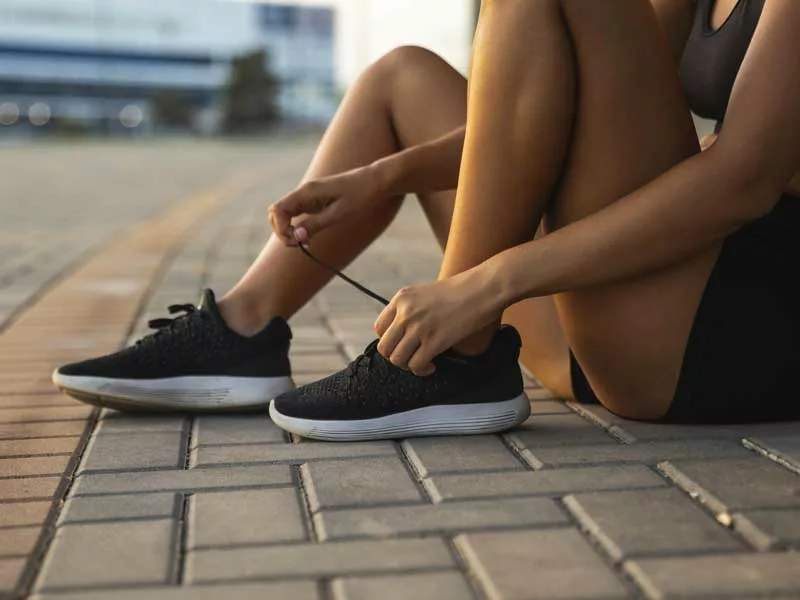 donna inizia a fare attività fisica e si allaccia le scarpe 