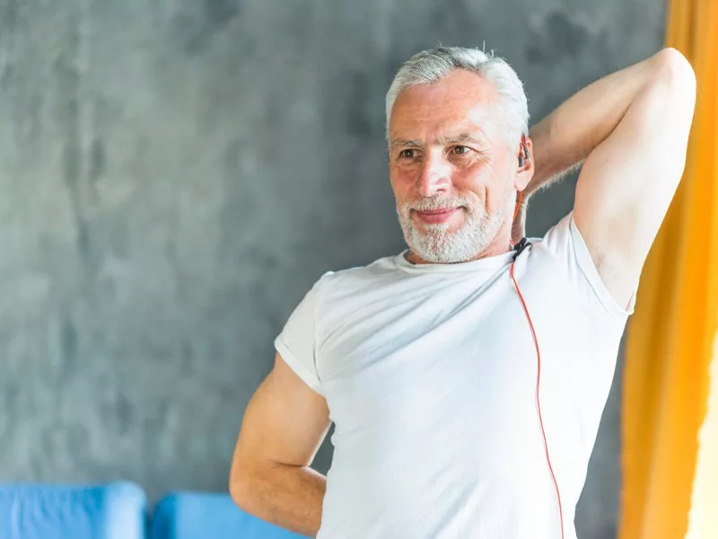 uomo di 50 anni che fa stretcing felice in palestra
