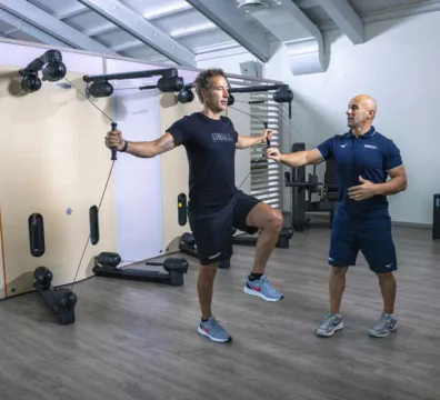 uomo felice in palestra si allena con personal trainer perché il movimento è salute