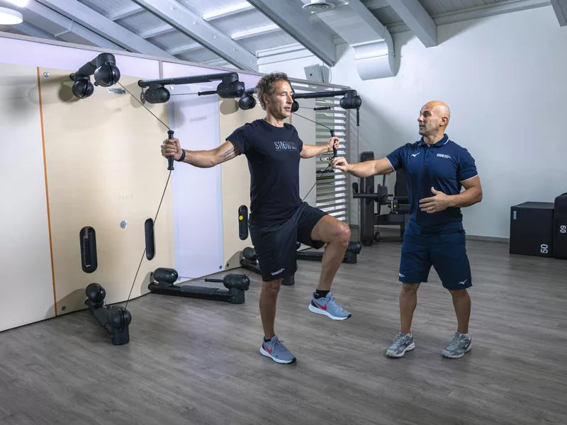 uomo felice in palestra si allena con personal trainer perché il movimento è salute