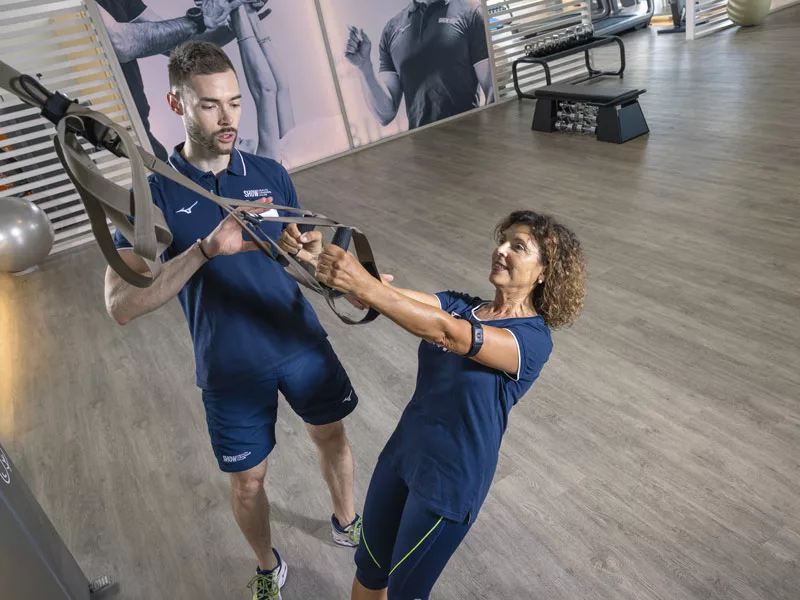 donna si allena seguita da un personal trainer  in palestra 