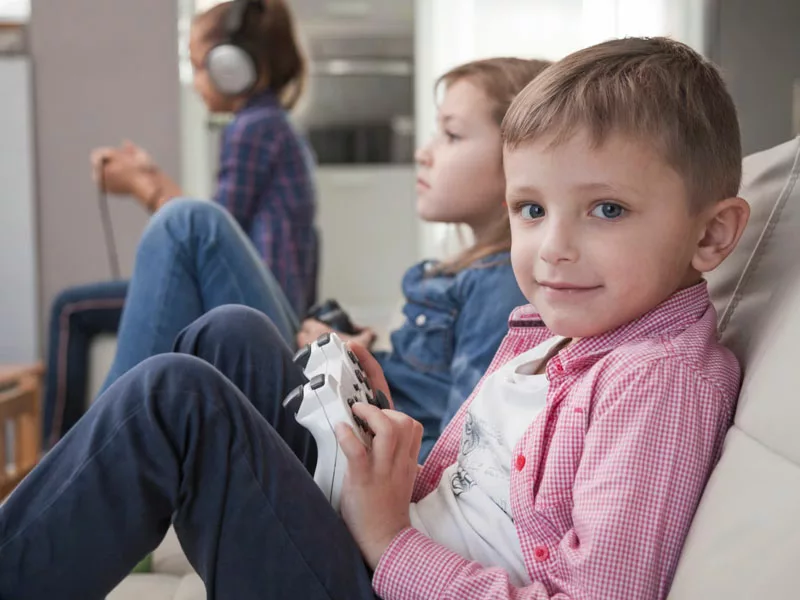 bambino seduto in divano gioca con i videogiochi