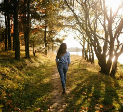 donna cammina in un bosco in autunno e compatte la sedentarietà