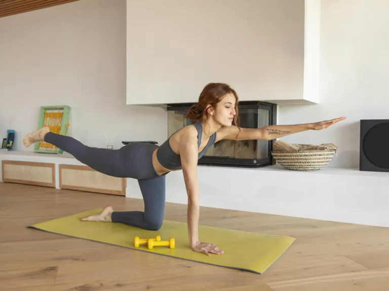 donna si allena a casa con tappetino per rimettersi in forma dopo le vacanze estive
