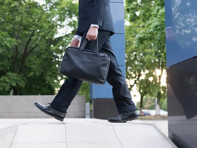 uomo cammina verso la macchina a piedi e ha uno stile di vita attivo 