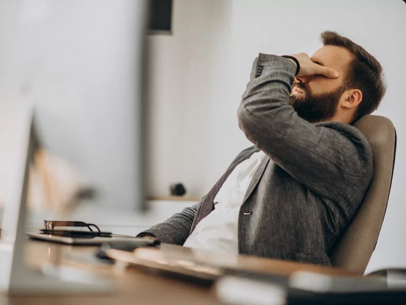 uomo seduto in ufficio è stanco 