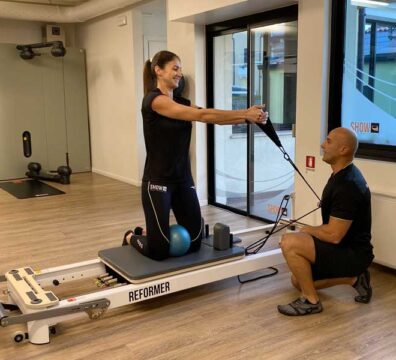 donna si allena seguita da un personal trainer e fa esercizi di pilates reformer