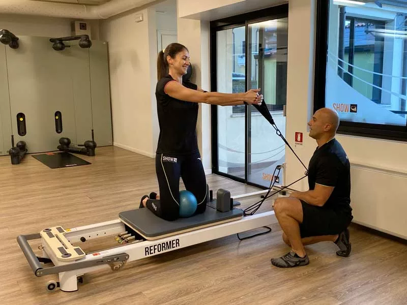 donna si allena seguita da un personal trainer e fa esercizi di pilates reformer