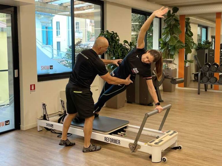 Donna sorridente fa insieme a personal trainer a Padova Reformer pilates