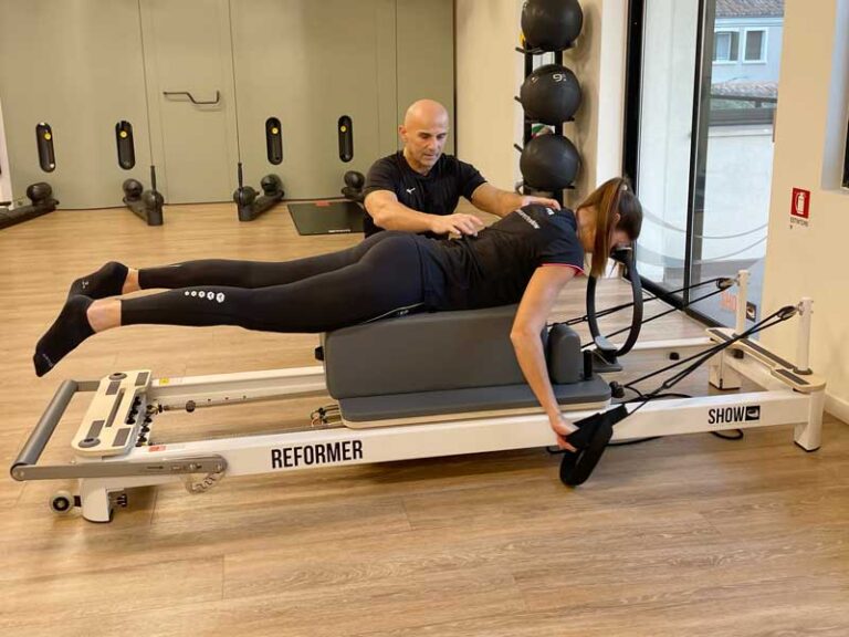 donna si allena in palestra seguita da personal trainer e prova i benefici del reformer pilates