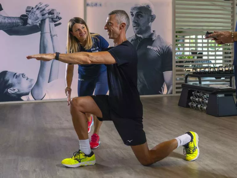 uomo sorridente si allena in palestra a Treviso, Sta facendo un allenamento semplice dedicato alle gambe seguito dalla sua personal trainer