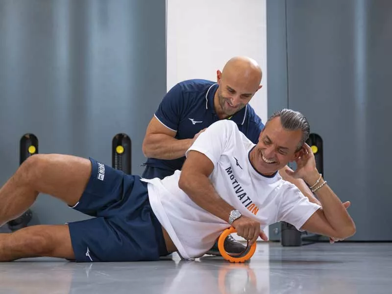 uomo si allena a show club una palestra a Padova. è felice e sorride mentre si allena seguito passo dopo passo dal suo personal trainer