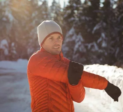uomo bello e sorridente in inverno da stretching prima di allenarsi