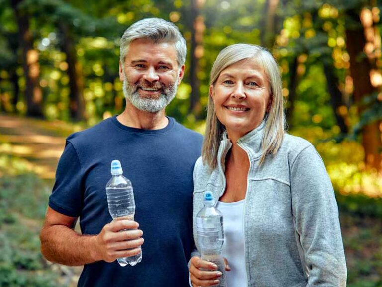 Uomo e donna sorridenti dopo l’allenamento, riflettono energia e benessere.