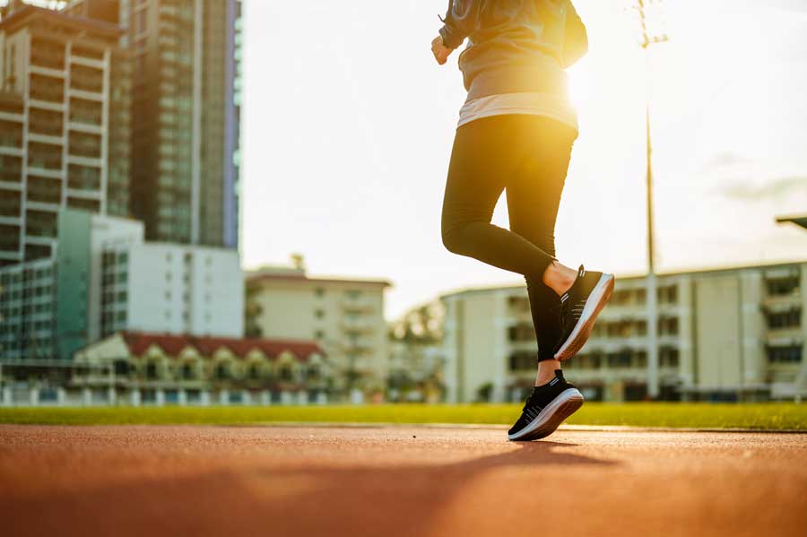 Primi piani dei piedi di una donna che corre al tramonto durante il running.
