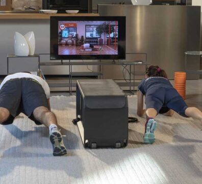 Una coppia, uomo e donna, si allena a casa in salotto eseguendo un esercizio di plank.