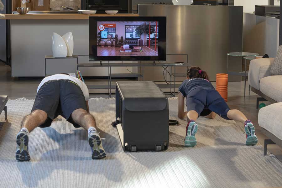 Una coppia, uomo e donna, si allena a casa in salotto eseguendo un esercizio di plank.