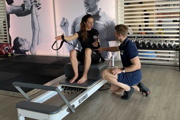 donna fa una lezione di reformer pilates seguita da un personal trainer