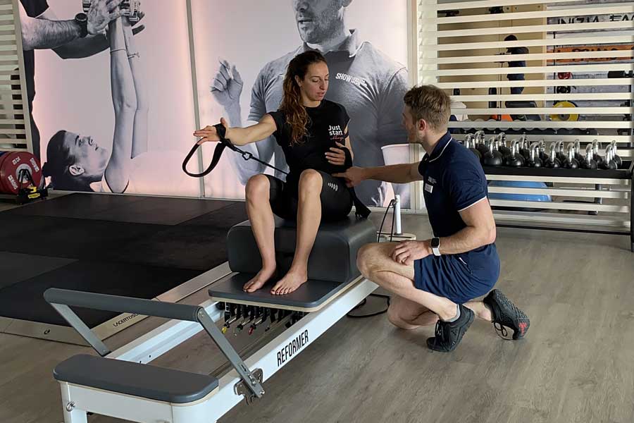 donna fa una lezione di reformer pilates seguita da un personal trainer